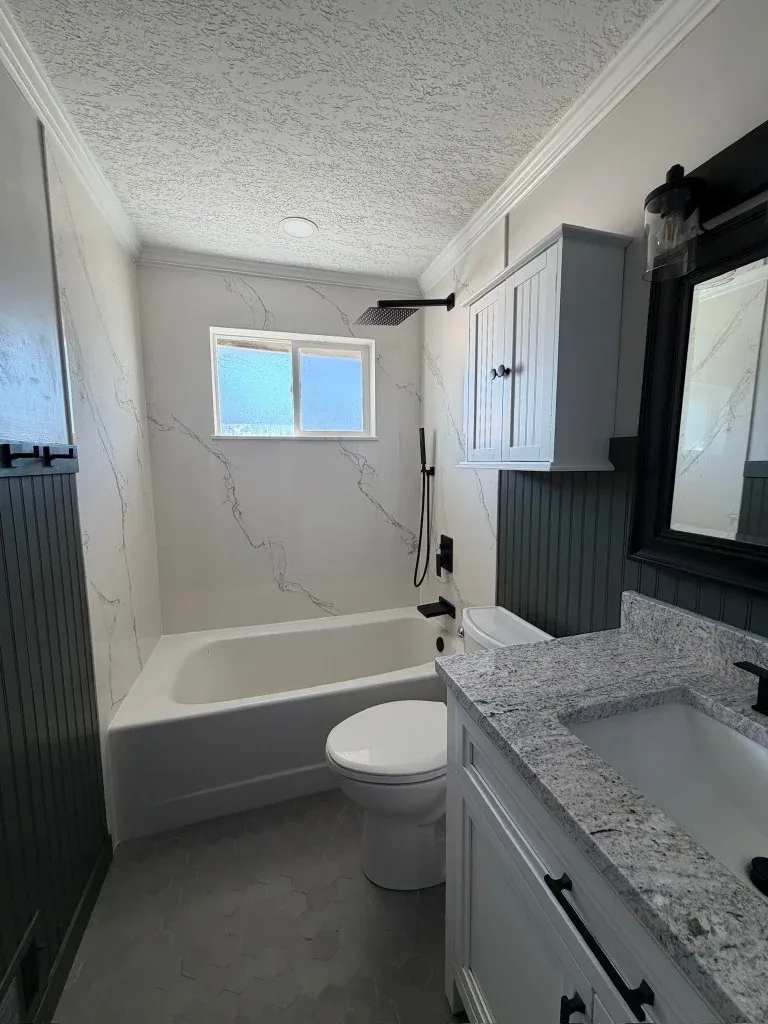 Bathroom remodel with marble tile shower, white vanity, and matte black fixtures in a Utah home
